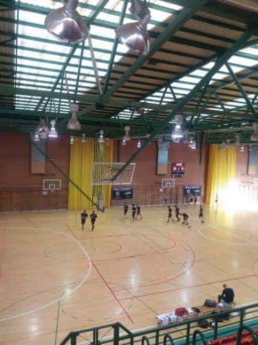Vista interior del polideportivo con cancha de baloncesto y gradas