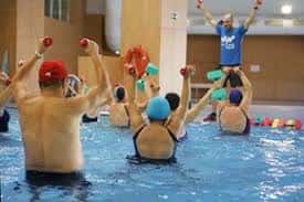 Sesión de ejercicio acuático con monitores y participantes en el agua
