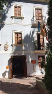 Entrada lateral del edificio con balcones y banderas colgantes