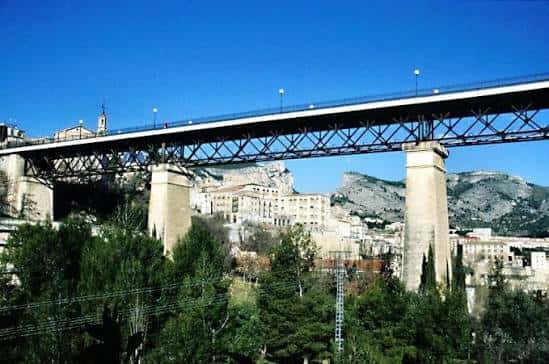 El viaducto en primer plano contra un cielo azul intenso, mostrando su diseño arquitectónico y el entorno montañoso