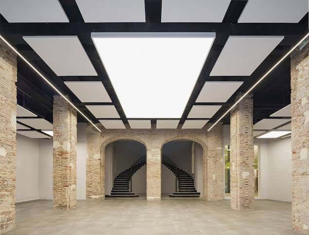 Espacio interior amplio con columnas de ladrillo original y escaleras dobles bajo techo moderno