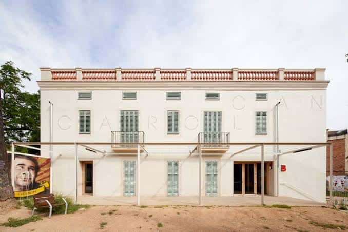 Fachada principal del edificio Can Carol con persianas verdes y balcón central
