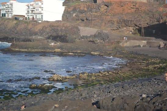 Costa de La Barranquera con playa de rocas y edificios blancos al fondo
