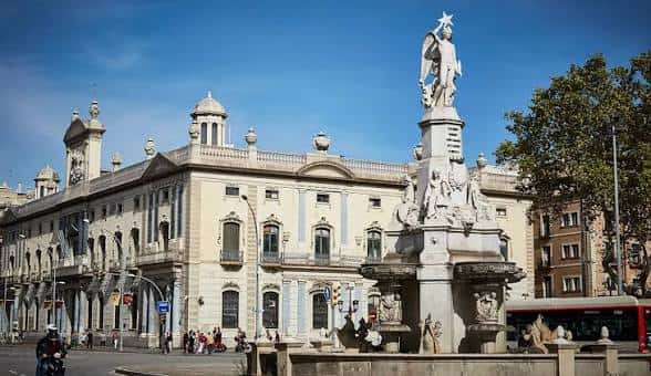 Fachada del edificio histórico junto a la fuente en la plaza