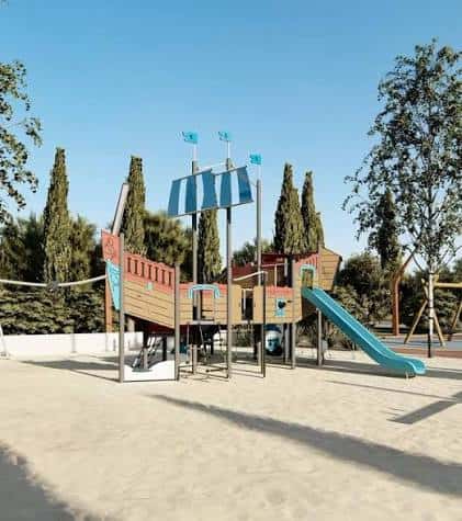 Área de juegos infantil con estructura de barco y tobogán en el Parc dels Xiprers