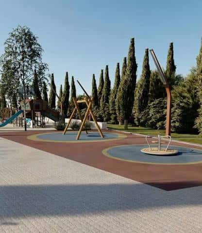 Zona de juegos infantiles con columpios y giratorias sobre suelo de caucho
