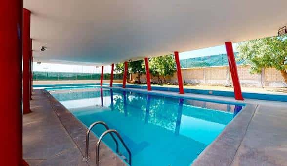 Piscina al aire libre con columnas rojas y vista a la naturaleza