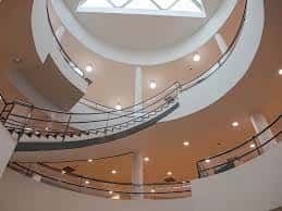 Interior con escalera espiral y atrio iluminado por claraboya