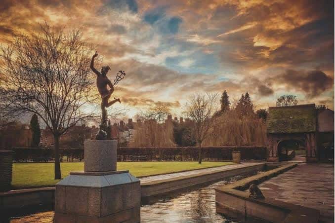 Escultura de un niño saltando junto a un estanque al atardecer en Rowntree Park