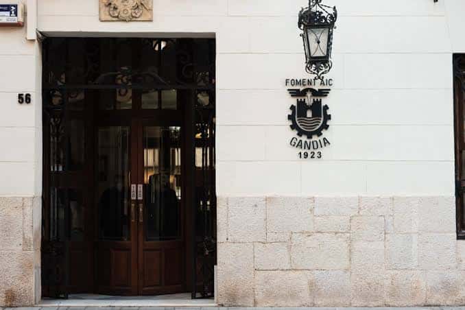 Entrada principal del Fomento AIC en Gandia con su distintivo escudo y farola