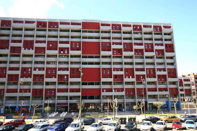 Vista frontal del edificio de viviendas en Plaza Pedro Astigarraga con fachada roja y blanca