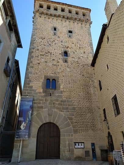 Fachada principal del torreón medieval con puerta de madera y ventanas góticas