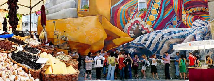 Vista panorámica del Mercado de la Almendra con puestos de productos locales y un mural colorido al fondo