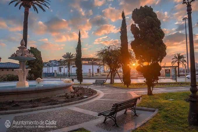 Plaza de las Tortugas con fuente, bancos y palmeras bajo cielo nublado