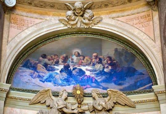 Detalle artístico de un fresco con la Última Cena enmarcado por elementos arquitectónicos y esculturas