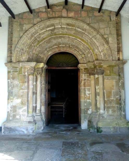 Portada románica de la iglesia con arco de triunfo y detalles arquitectónicos en piedra