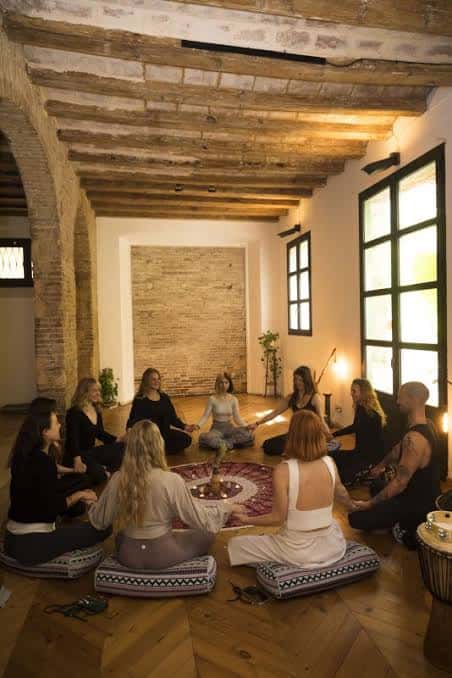Grupo de personas participando en un círculo de meditación o yoga en el interior del estudio