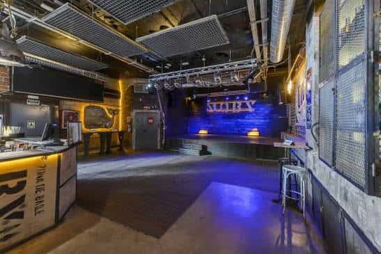 Vista panorámica del interior del club con escenario y barra de servicio