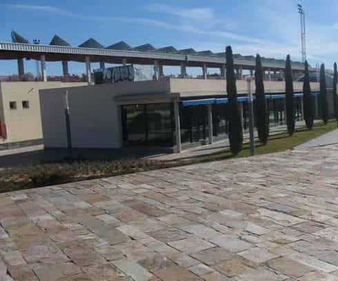 Fachada exterior del polideportivo con entrada principal y zona ajardinada