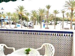 Terraza con mobiliario blanco y azulejos decorativos frente a la plaza