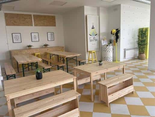 Interior del espacio TeePee Creatives con mesas de madera y decoración minimalista