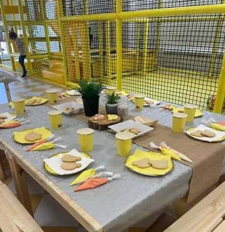 Mesa preparada para evento infantil en zona de juegos amarilla