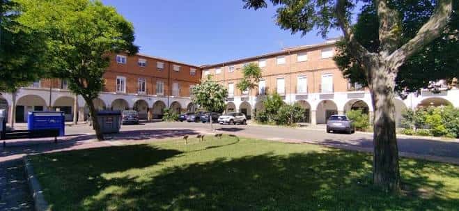 Vista diurna de la Plaza Porticada con arcos y árboles en primer plano