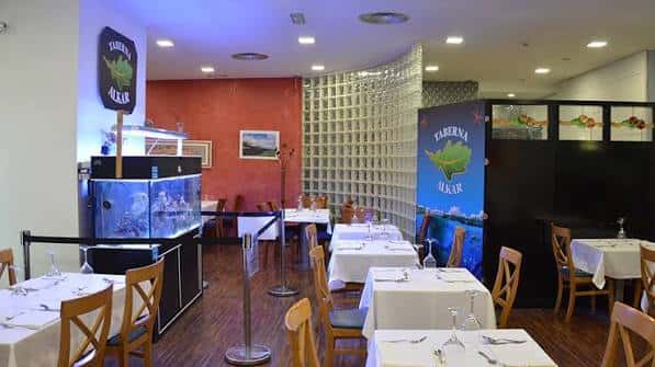 Interior del restaurante Taberna Alkar con mesas dispuestas para cena y decoración moderna