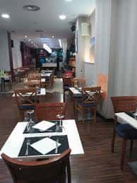 Vista del comedor principal con mesas cuadradas y sillas de madera