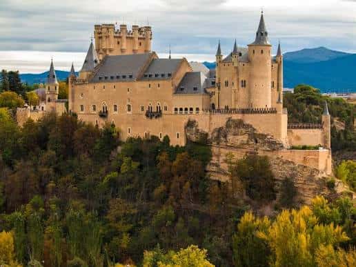 Vista panorámica del Alcázar de Segovia en otoño con montañas al fondo
