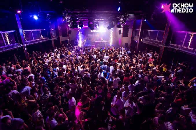 Vista general del interior de Ochoymedio Club con multitud de personas y luces de neón
