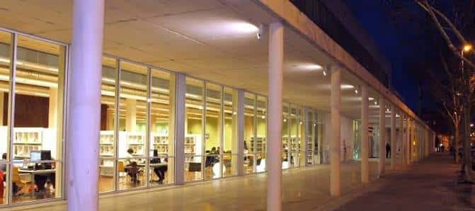 Fachada nocturna de la biblioteca iluminada desde el interior
