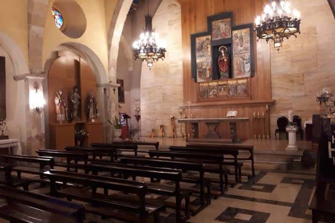 Vista del interior de la nave central con bancos de madera y decoración religiosa