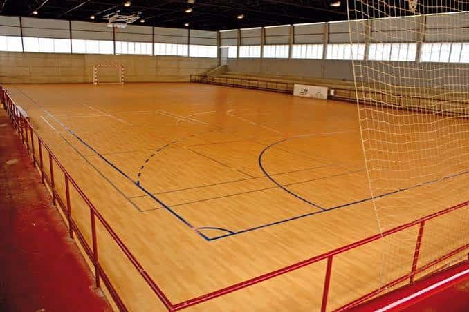 Vista del interior de la pista polideportiva con suelo de madera y gradas