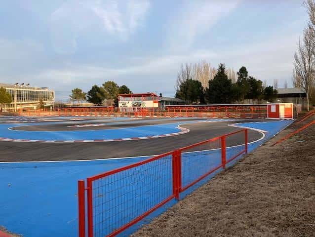 Pista de karting al aire libre con vallas rojas y césped circundante