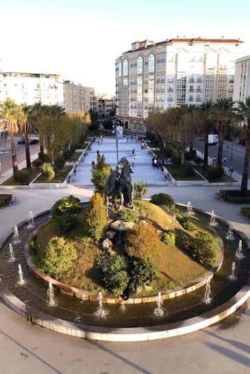 Perspectiva elevada de la plaza mostrando el monumento central y el paseo arbolado