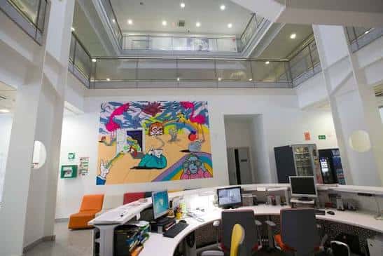 Área de coworking con mural artístico y puestos de trabajo modernos