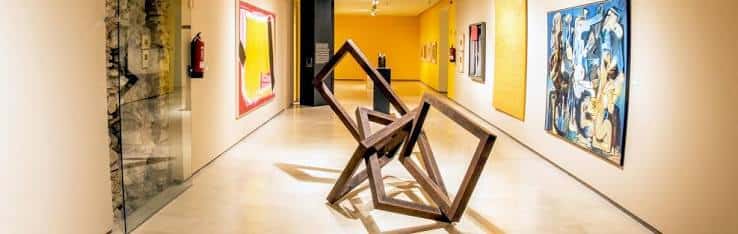 Galería de arte moderno con escultura abstracta y cuadros expuestos