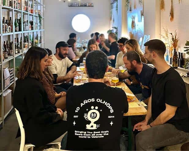 Vista desde atrás de un grupo sentado en mesa larga durante evento en Olhöps