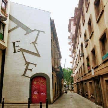 Fachada del Ateneu Hortenc con grafiti y puerta roja en Carrer de Pere Pau