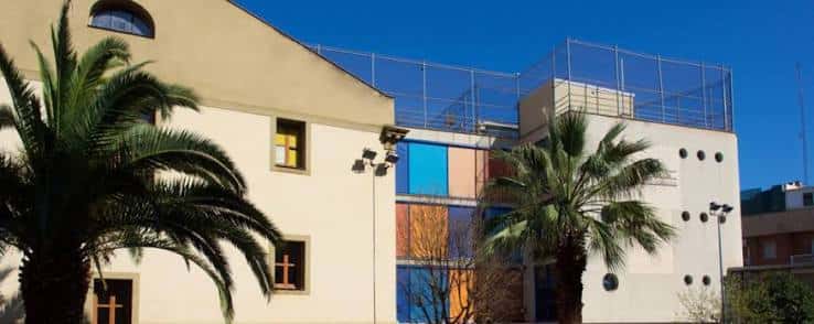 Vista exterior del edificio con fachada colorida y palmeras