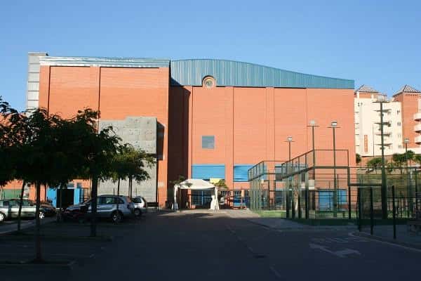 Vista exterior del Polideportivo Municipal El Carmen con su fachada de ladrillo y canchas deportivas al frente