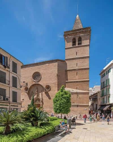 Vista exterior de la Basílica de Sant Miquel con su torre y fachada bajo un cielo azul