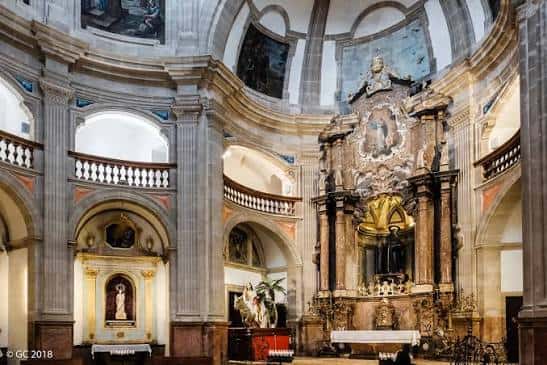 Interior de la nave central con bóvedas, columnas y altar barroco