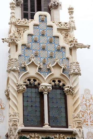 Detalle arquitectónico de la fachada con azulejos y esculturas en estilo modernista