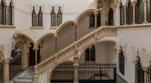 Escalera interior curva con arcos y columnas decorativas en el patio del Palau Macaya