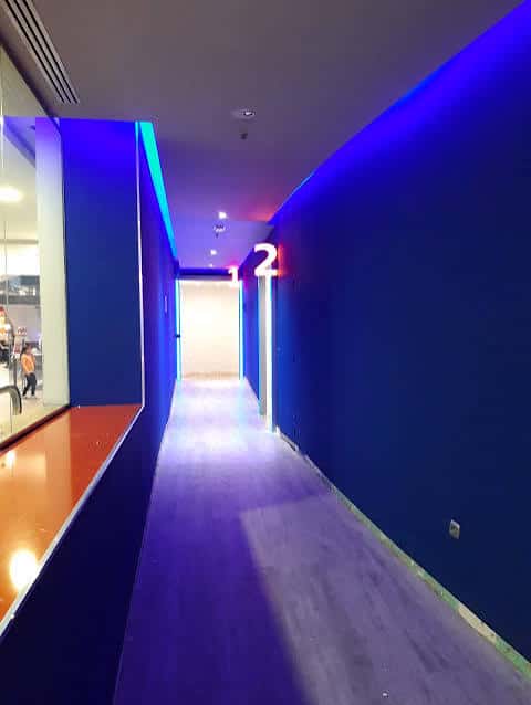 Pasillo interior del cine con iluminación azul y señalización de sala