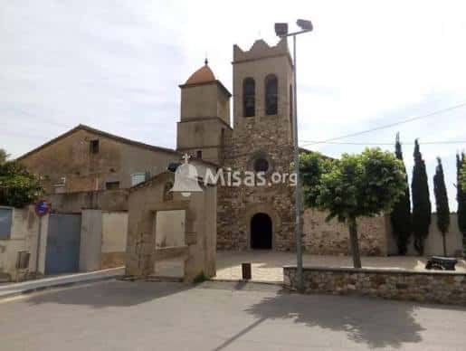 Fachada exterior de la iglesia de piedra con campanario y entorno rural