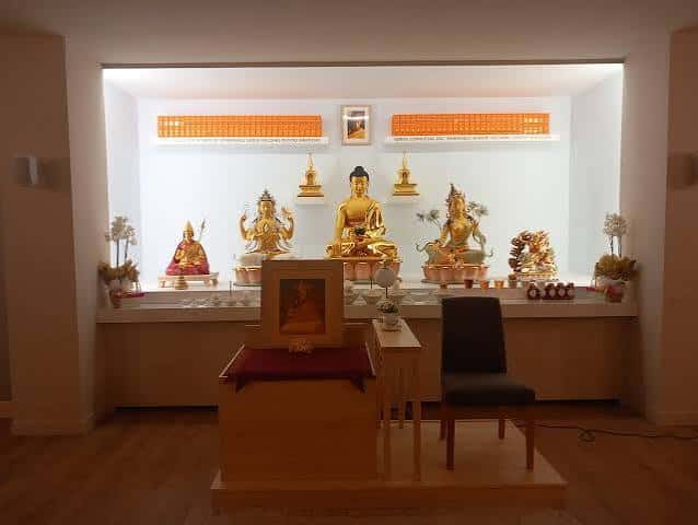Sala de meditación con altar principal y estatuas doradas