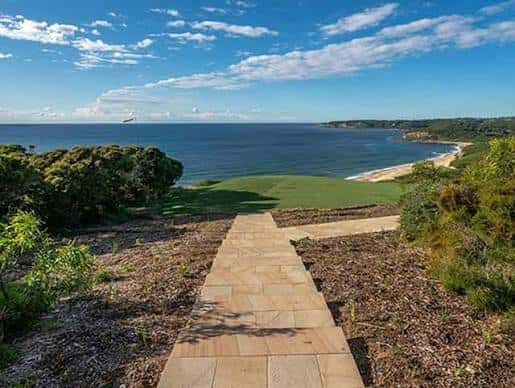 Camino pavimentado que conduce hacia una vista despejada del mar y la playa